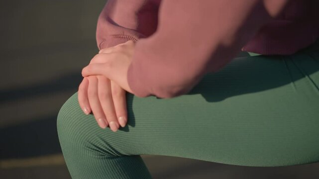Close up of young person engaging in fitness exercise, kneeling forward with hands resting on knee, shadows cast on ground creating dynamic focus on healthy lifestyle and workout movement