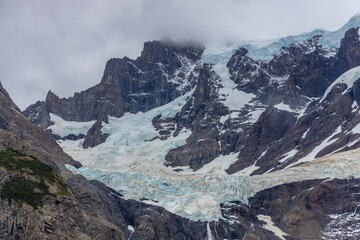 Obraz premium Torres del Paine national park mountain landscape in Patagonia, Chile. Los Cuernos and Torres del Paine peak granite towering summits on a nasty and sunny day above the blue water lake in the Andes