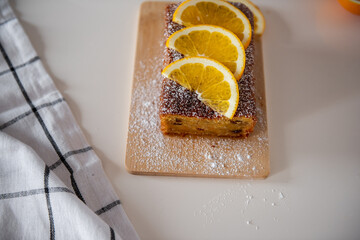 Top view of freshly baked orange cake topped with sliced oranges and dusted with powdered sugar...