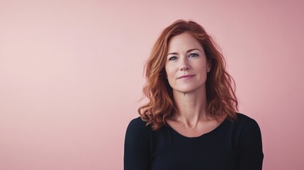 Fototapeta premium Confident Woman with Red Hair Posing Against a Soft Pink Background