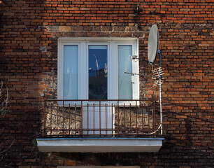 Balcony with Satellite Dish and Antenna on Brick Wall Building, Symbolizing Urban Living and...