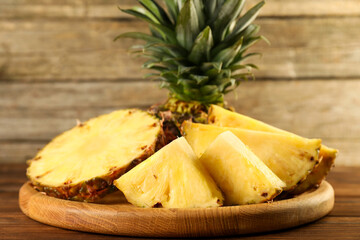 Cut fresh ripe pineapple on wooden table, closeup
