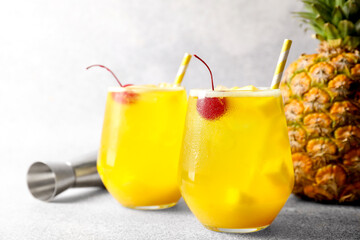 Tasty pineapple cocktail with cherry in glasses on gray table, closeup