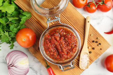 Spicy salsa and ingredients on white table, top view