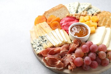 Different types of cut cheese and other snacks on light textured table, closeup