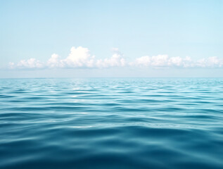 A serene and vast ocean with clear blue waters, calm waves, and a beautiful sky, perfect for relaxation and inspiring peaceful moments in nature