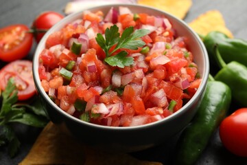 Delicious salsa in bowl and ingredients on grey table, closeup
