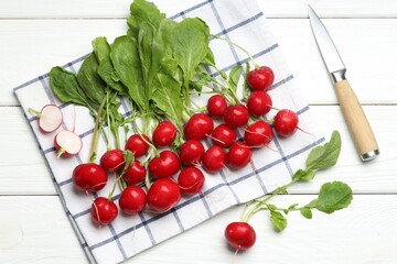 Many fresh radishes and knife on white wooden table, flat lay