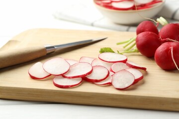 Many fresh radishes and knife on white table, closeup