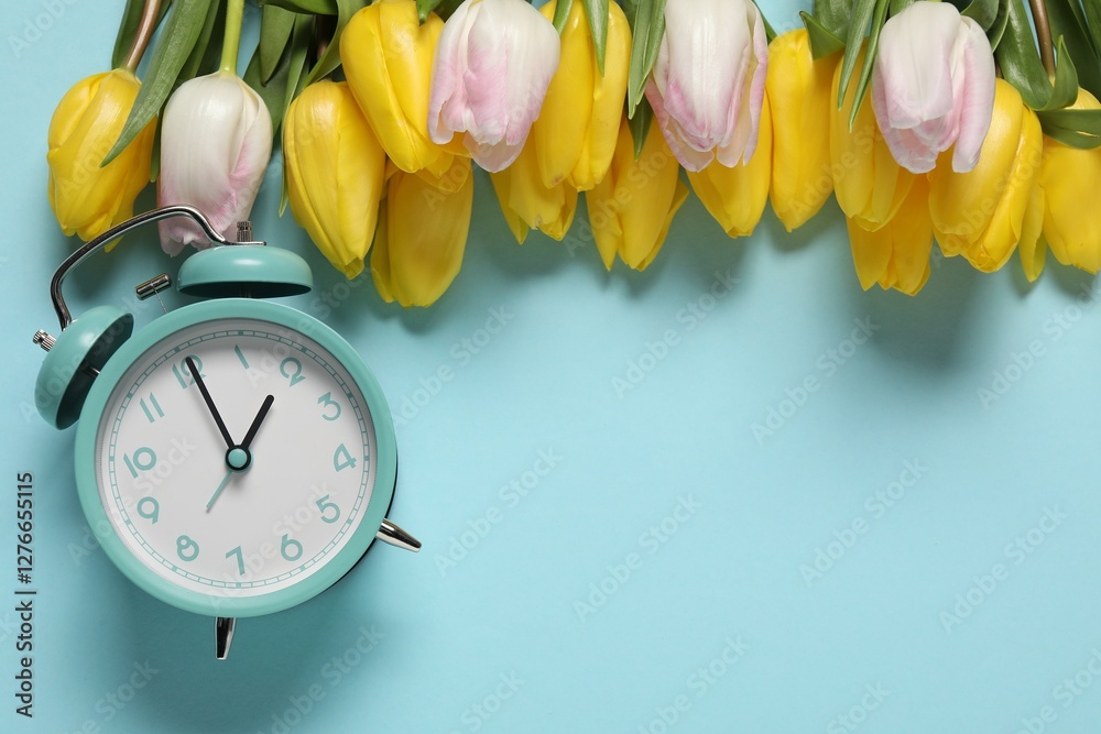 Poster spring time. alarm clock and beautiful tulips on light blue background, flat lay. space for text