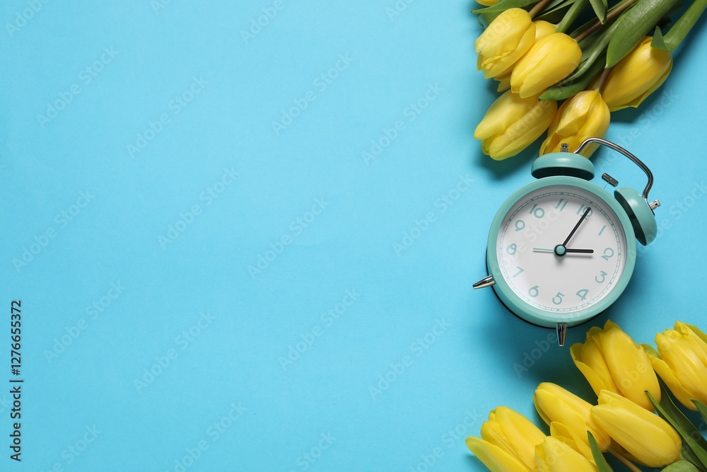 Poster spring time. alarm clock and beautiful tulips on light blue background, flat lay. space for text