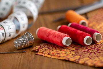 Sewing kit - colorful yarns, fabric, needle and measuring tape on a rustic wooden table