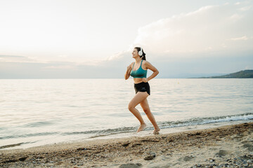 Young woman running or jogging on the beach at sunset	