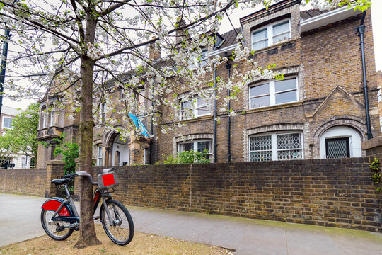 Vintage Bicycle Parked by a Tree in Front of Historical Brick Building in London
