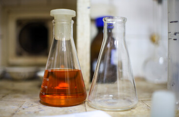 A chemical flask with reagent next to the same empty flask in the old chemical laboratory
