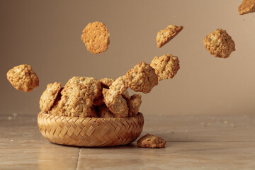 Oatmeal cookies in motion on a beige background.