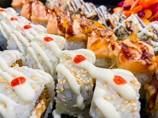 A plate of sushi with a white sauce and red sauce on top