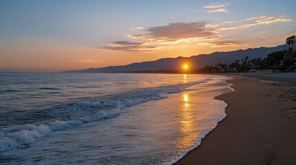 Waves gently crash on the sandy beach as the orange sun sets over the ocean, illuminating the surrounding mountains in a tranquil setting