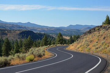 Naklejka premium A long and curvy road winding through the mountains on a sunny day
