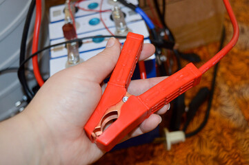 hand holding red jumper cable clamp battery system connected wiring setting technical electrical...