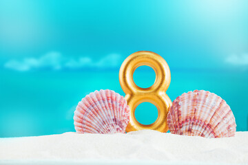 golden number 8 stands on soft sand, by large pink seashells, against backdrop of calm blue sea on sunny day. Celebration, nature, International Women's Day, birthday, hot country, summer vacations