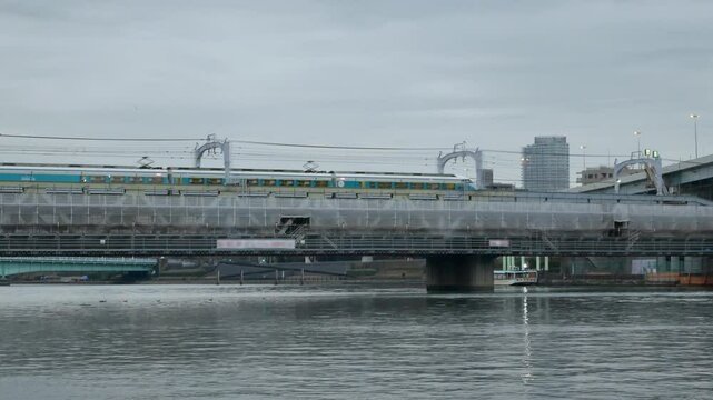 sumida river view with public train transportation on railway track crossing river in the city of Tokyo in Japan in winter cloudy daytime