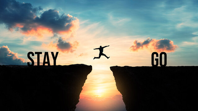 Silhouette of a person jumping from stay to go over a gap between cliffs at sunset, making life decisions, embracing change, leaving the comfort zone, moving forward, taking risks for a better future
