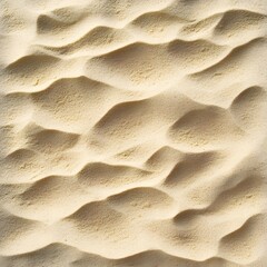 Close-up of rippled sand texture.  Sunlit, beige and tan grains create wave-like patterns on a sandy surface.