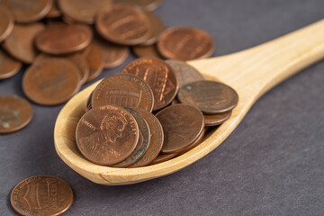 Wooden spoon filled with US pennies on a dark background, symbolizing financial savings, budgeting, and investment concepts.
