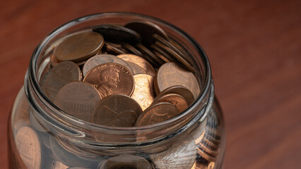 Glass jar filled with US pennies, symbolizing savings, financial security, and wealth accumulation.
