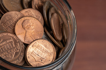 Close-up of a glass jar filled with US pennies, representing savings, financial security, and...
