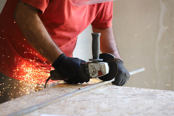 Close-up photograph of latin man cutting iron with electric grinder that produces sparks