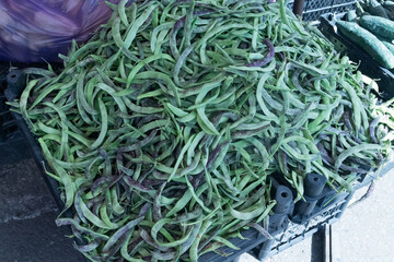 A mountain of green asparagus bean pods at a farmer's market in a southern country