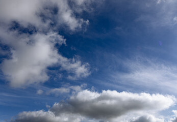 Obraz premium The sky is endless and deep blue, with cotton-like clouds scattered. Some clouds are light and airy, while others are dense, making the scene visually rich.