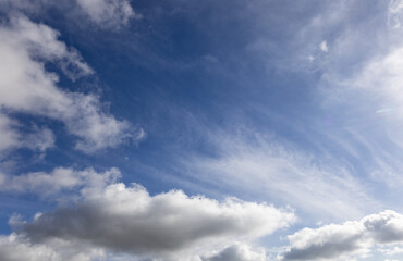 The sky is endless and deep blue, with cotton-like clouds scattered. Some clouds are light and airy, while others are dense, making the scene visually rich.