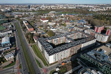 An aerial view of Kraków’s Zabłocie district, showcasing its dynamic transformation along the banks of the Vistula River. Once an industrial area, Zabłocie has evolved into a modern, thriving neighbor