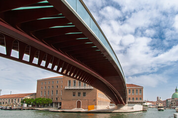 Modern constitution bridge spanning over a canal in venice, italy, with historic buildings and a cloudy sky