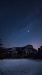 Fototapeta premium Clear Night Sky Over A Snowy Field With A Mountain In The Distance