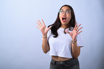 A young Asian woman with glasses and long dark hair, wearing a white crop top, makes a surprised...