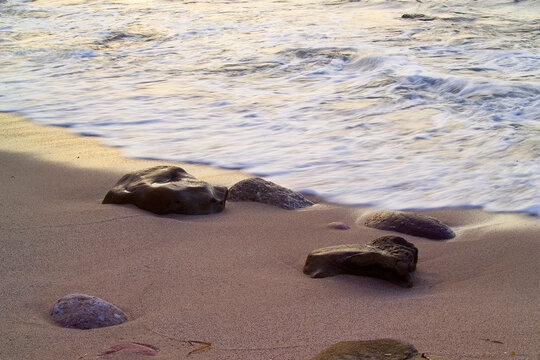 sand beach rocks and sea Waves of the undertow in Porticciolo. Alghero. Sardinia. Italy