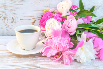 Happy mother's day concept: bunch of pink and purple peonies flowers and white cup of coffee on white paint wooden table