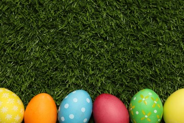 Beautiful decorated Easter eggs on green grass, flat lay. Space for text
