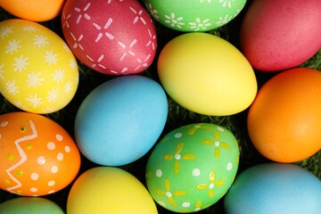 Beautiful decorated Easter eggs on green grass, flat lay