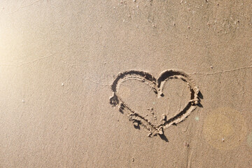 Heart drawn in sand on empty tropical beach during sunset. Vacation and Travel Concept. Valentines Day or Wedding concept.