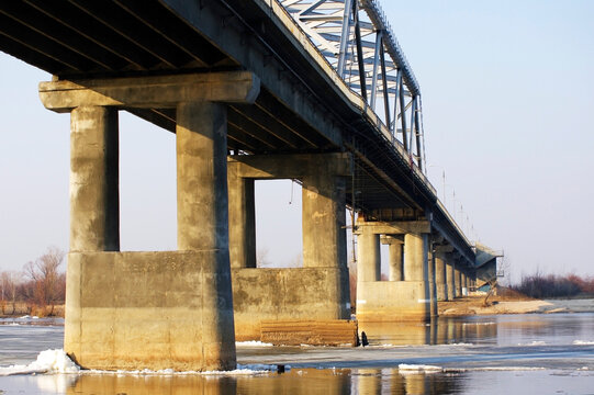 Concrete bridge over the river with ice floes floating in the spring during the melting of ice