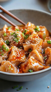 Japanese gedza in a savory sauce topped with sesame seeds on a light gray background. Chinese Jiaozi dumplings 