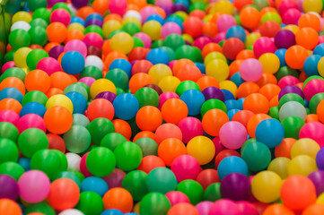 Background of many plastic colorful and multicolored round balls in children's playroom for kids to play. Photography, childhood concept.