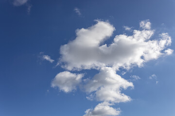 The sky is bright blue with soft, white clouds drifting gently. Some clouds are thin and wispy, while others are thick and fluffy, creating a peaceful view