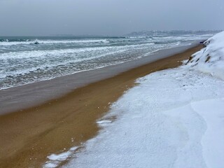 waves and winter on the snow covered beach