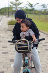 Obraz premium Mother Teaching Her Child to Ride a Bicycle Outdoors